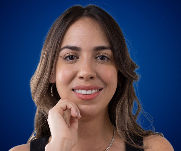 Portrait of Alejandra Tejeda, a speaker and ontological coach, with a blue background.