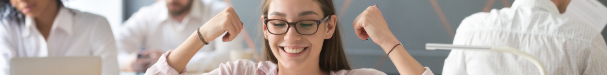 Mujer sonriente con gafas mostrando fuerza con los brazos, reflejando full motivación en un entorno laboral.